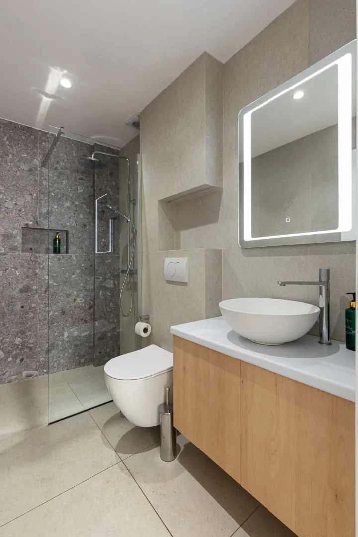 Savremeno opremljeno kupatilo sa tuš kabinom, umivaonikom i WC šoljom.