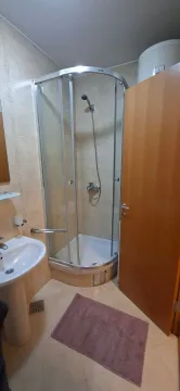 Small bathroom with a shower cabin, sink, and water heater. - image 6