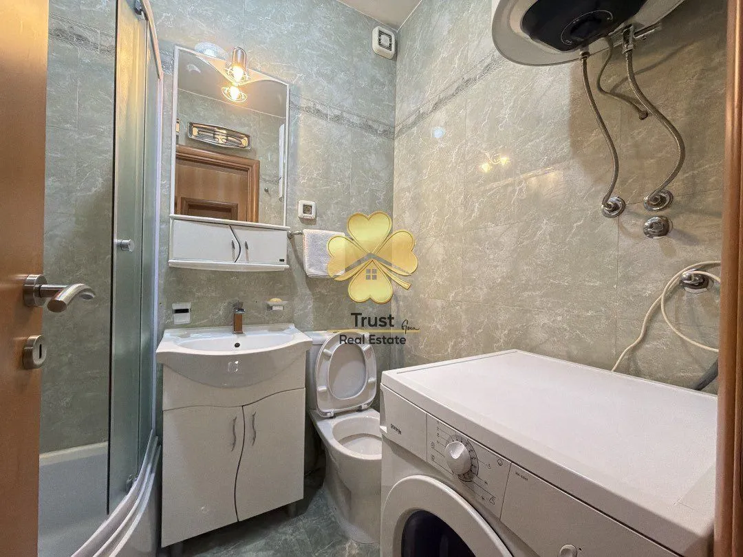 Smaller bathroom with a sink, toilet, shower cabin, and washing machine.