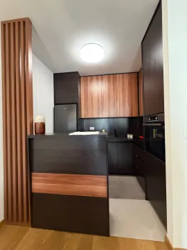 Modern dark-toned kitchen with wooden elements and an integrated refrigerator. - image 3