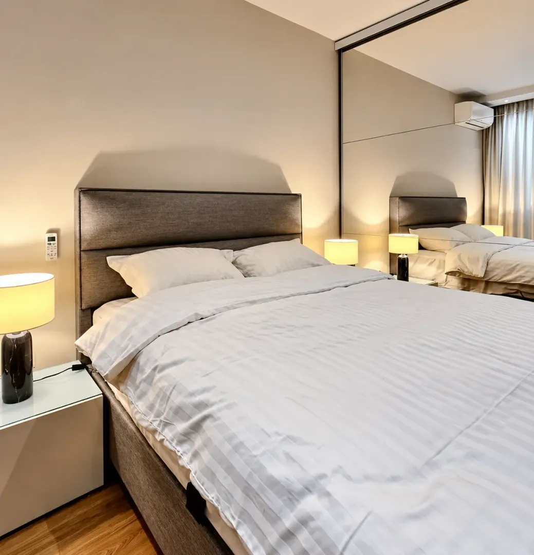 Modern bedroom with a double bed, bedside tables and a large mirror.