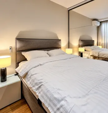Modern bedroom with a double bed, bedside tables and a large mirror. - image 4