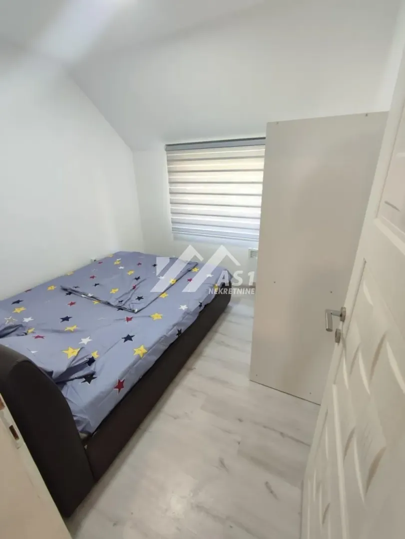 Manja spavaća soba sa krevetom i garderoberom u potkrovlju.