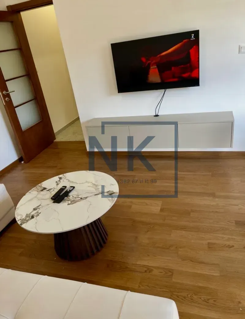 Living room with a sofa, coffee table, and wall-mounted TV.