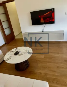 Living room with a sofa, coffee table, and wall-mounted TV. - image 2