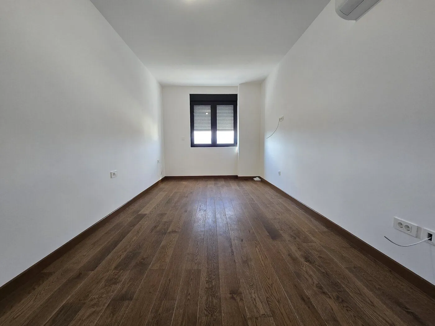 Empty room with white walls and wooden flooring.