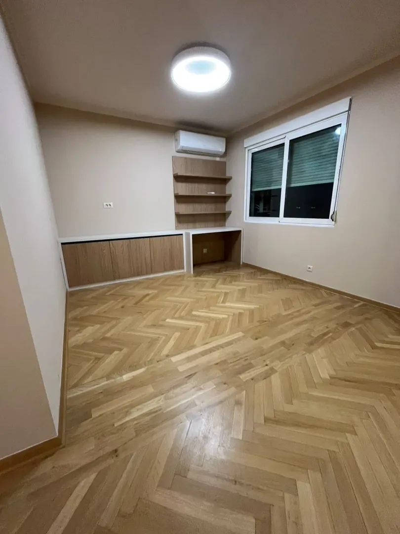 Prazna soba sa drvenim podom, ugradnim elementima i klima uređajem.