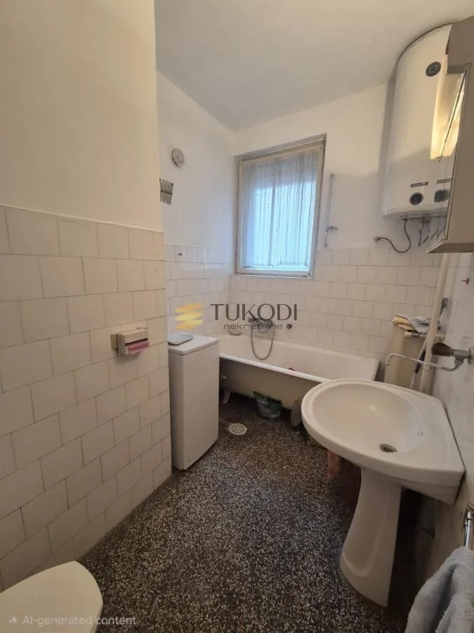 Starije kupatilo sa kadom, umivaonikom i bojlerom.