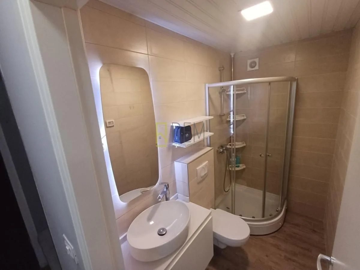 Manje kupatilo sa tuš kabinom, umivaonikom i WC šoljom.