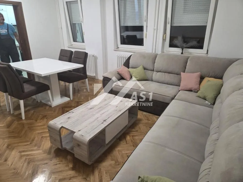 Dnevna soba sa garniturom, stočićem i trpezarijskim stolom sa stolicama.