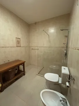 Spacious bathroom with a walk-in shower, toilet, and wooden vanity. - image 6