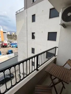Manji namješteni balkon sa drvenim stolom i stolicama i pogledom na okolne zgrade. - image 8