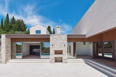 Pogled na spoljašnjost moderne kuće sa kamenim stubovima i terasom. - image 3
