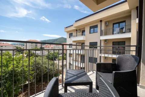 Namješten balkon sa garniturom za sjedenje i pogledom na okolne zgrade i brda. - image 2