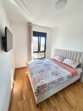 Spavaća soba sa bračnim krevetom i televizorom na zidu. - image 3