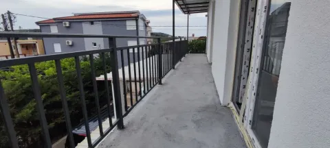 Long balcony with a metal railing and a view of surrounding buildings and greenery. - image 8