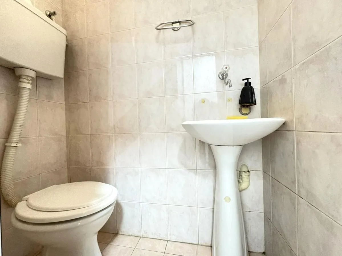 Small tiled bathroom with a toilet and a pedestal sink.
