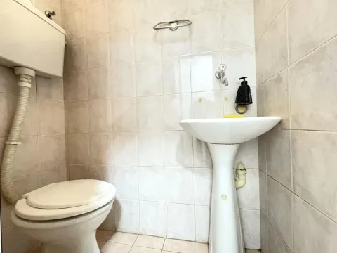 Small tiled bathroom with a toilet and a pedestal sink. - image 5