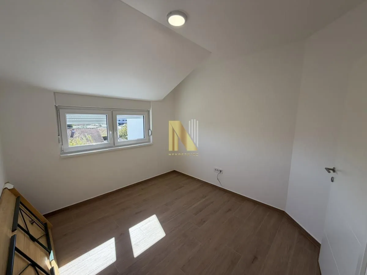 Empty room with a sloped ceiling and wooden flooring.