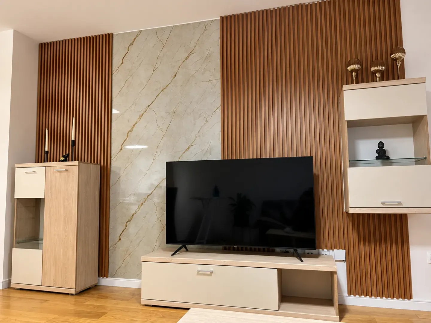 Dnevna soba sa TV-om i modernim drvenim panelima na zidu.