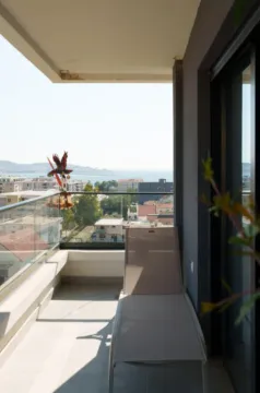 Natkriveni balkon sa ležaljkom i pogledom na grad i more. - image 9