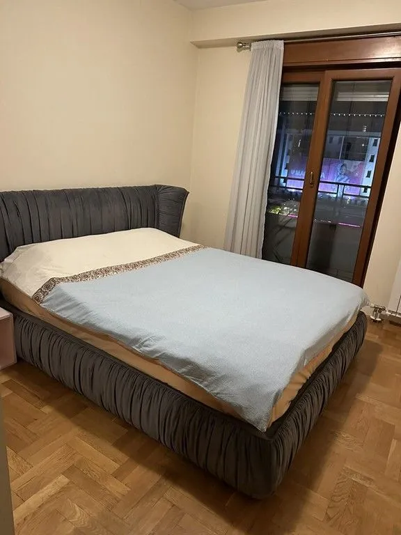 Spavaća soba sa bračnim krevetom i balkonskim vratima.