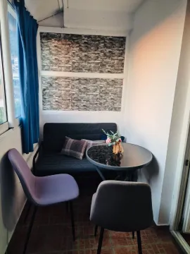 Enclosed balcony with seating furniture and a small table. - image 7