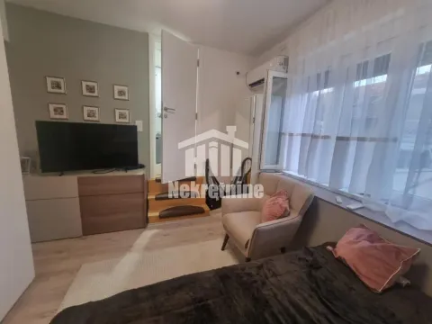 Nameštena spavaća soba sa krevetom, foteljom i televizorom. - image 9