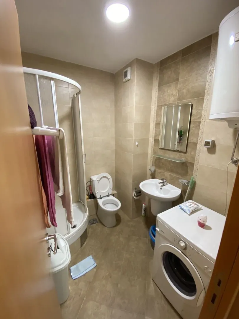 A functional bathroom equipped with a shower cabin, sink, and washing machine.