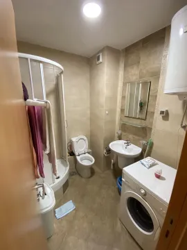 A functional bathroom equipped with a shower cabin, sink, and washing machine. - image 6