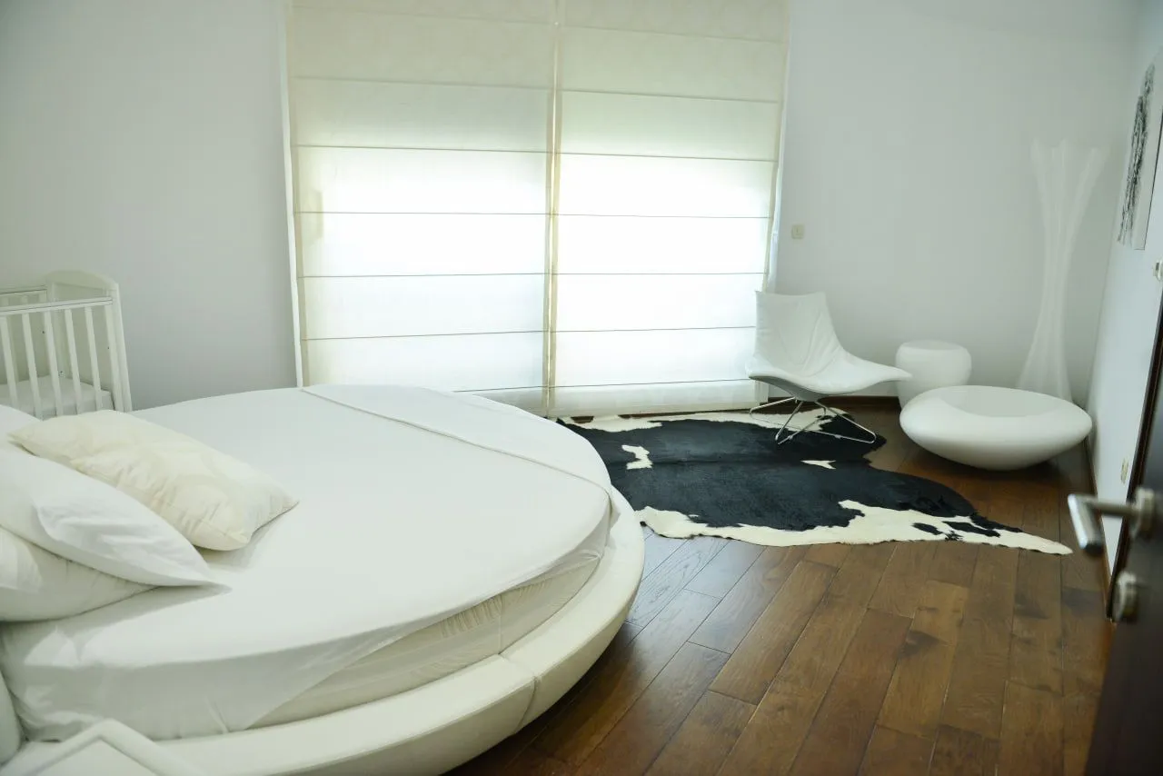 Spavaća soba sa okruglim krevetom i modernim namještajem.