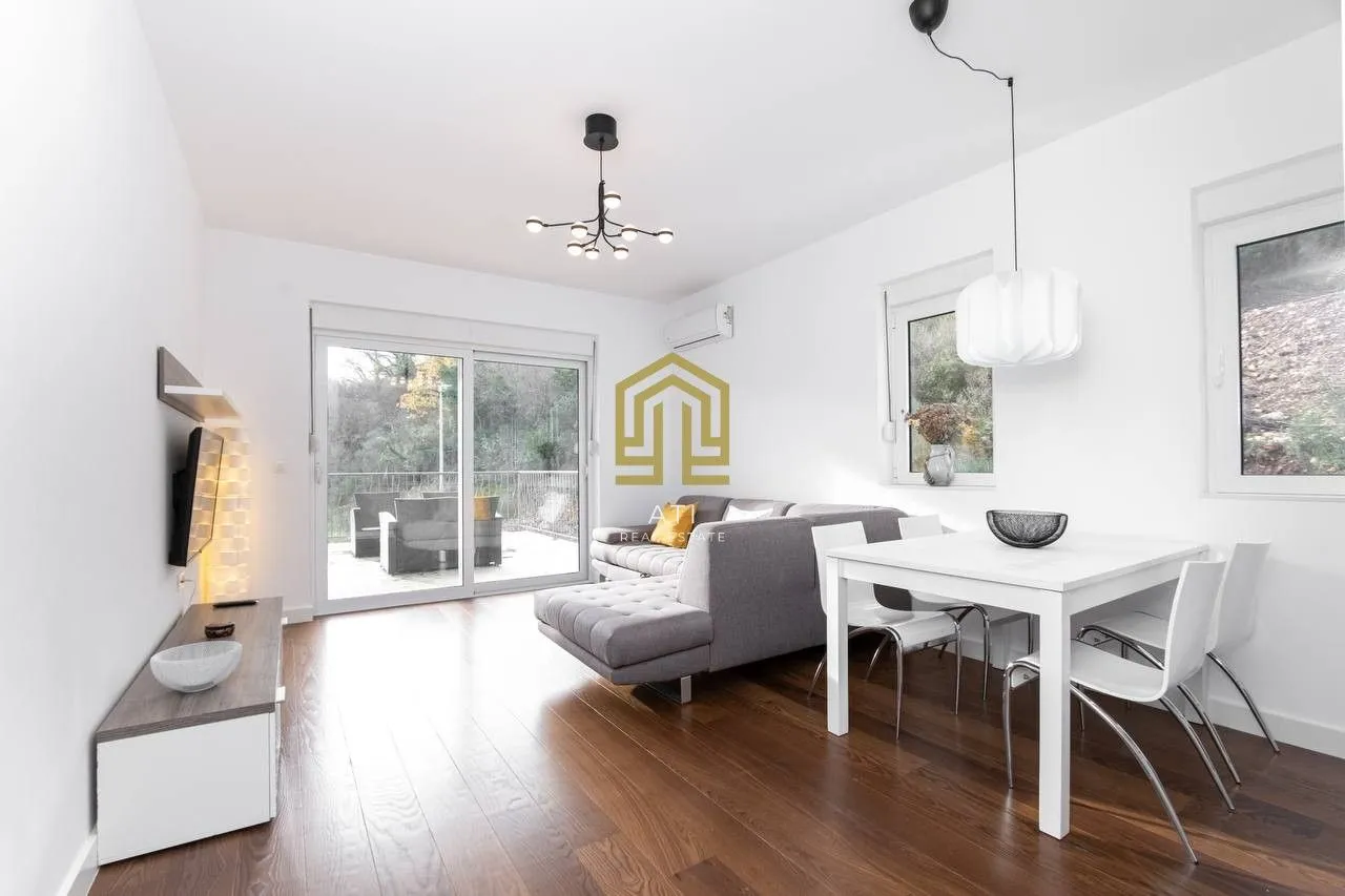 Living room with a sofa set, dining area, and access to the terrace.