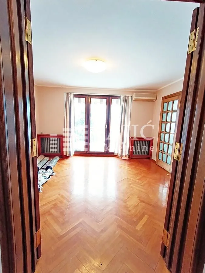 Empty room with wooden parquet flooring and windows.