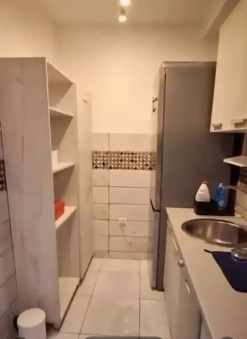 Manja kuhinja sa sudoperom, frižiderom i policama.