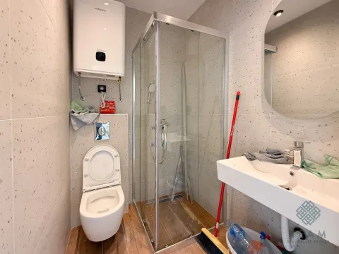 Bathroom equipped with a shower cabin, washbasin, toilet, and water heater. - image 4
