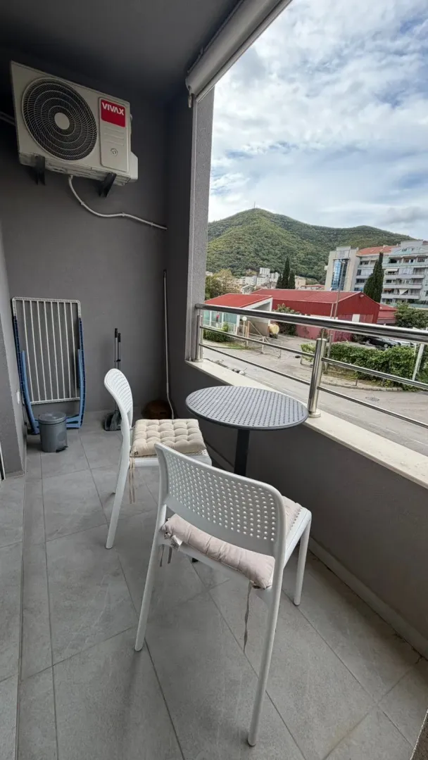 Small furnished balcony with a table, chairs, and a view of the surroundings.