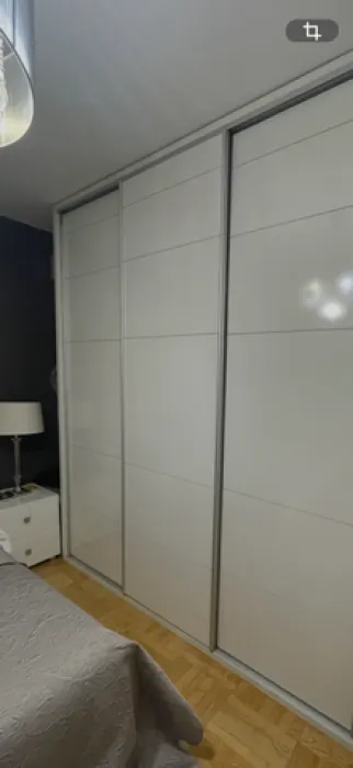 Spavaća soba sa velikim ugradnim garderoberom sa kliznim vratima.