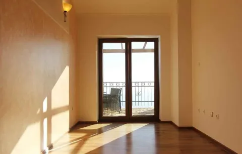 Prazna soba sa drvenim podom i staklenim vratima koja vode na balkon. - image 9