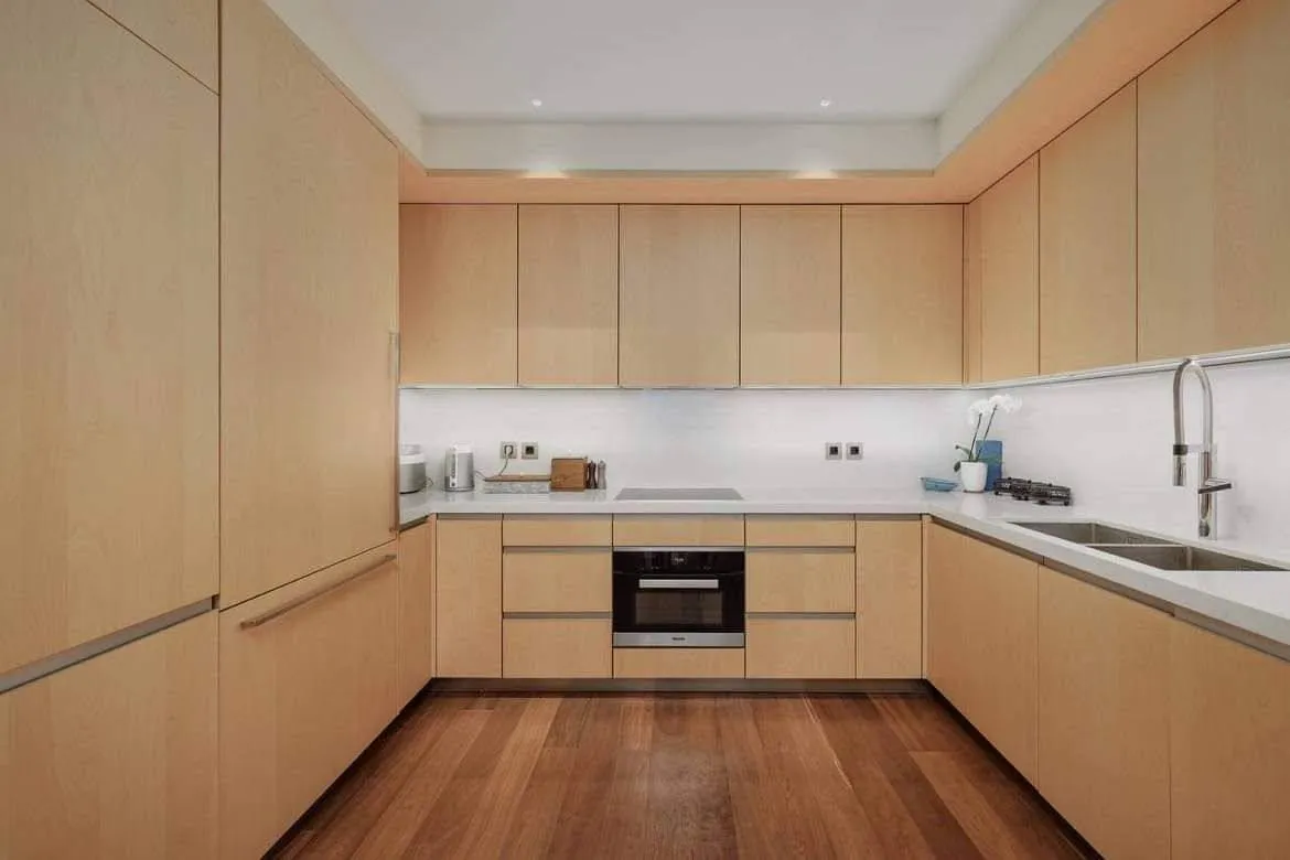Moderna kuhinja sa drvenim elementima u obliku slova U i ugradnim aparatima.