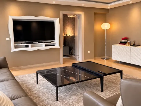 Dnevna soba sa garniturom, TV-om montiranim na zid i stočićima. - image 5