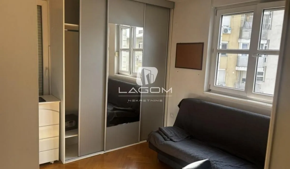 Smaller bedroom with a pull-out sofa and a large wardrobe with a mirror.