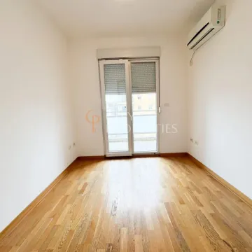 Empty room with wooden flooring, air conditioning, and balcony doors. - image 6