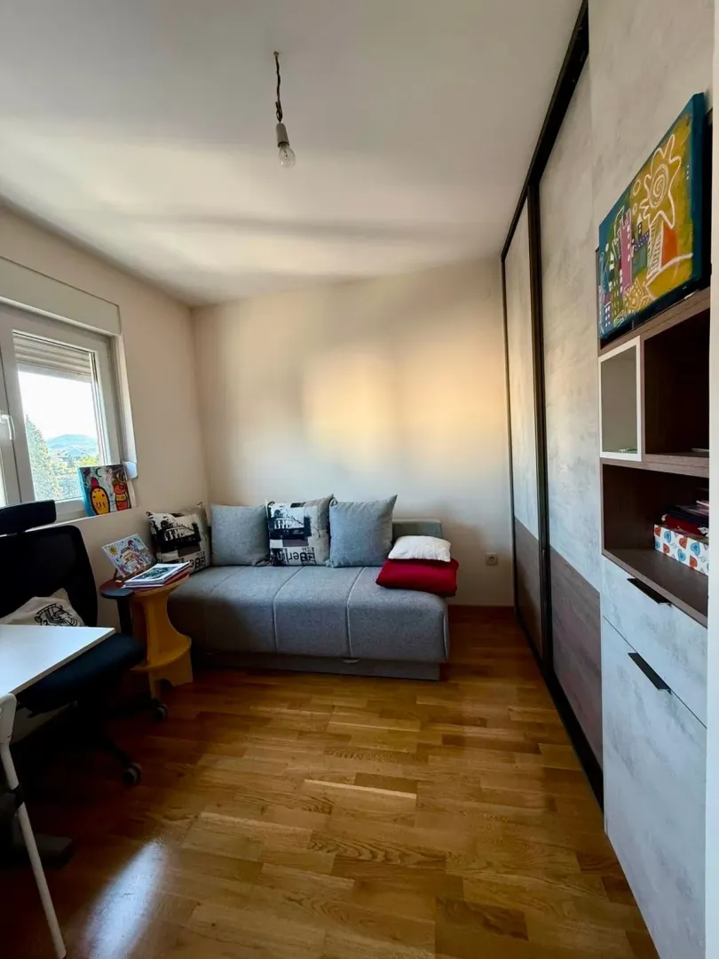 Smaller bedroom with a pull-out sofa bed, desk, and large built-in wardrobe.