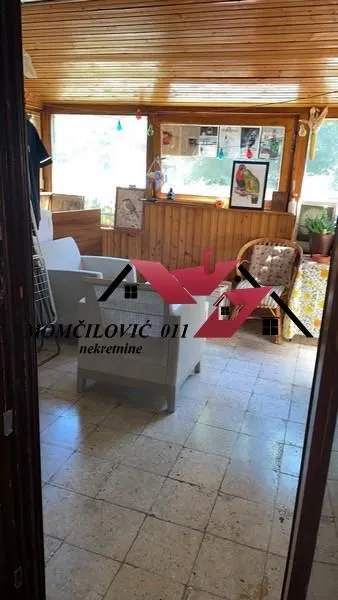 Zastakljena terasa sa drvenom oblogom na zidovima i plafonu i garniturom za sedenje.