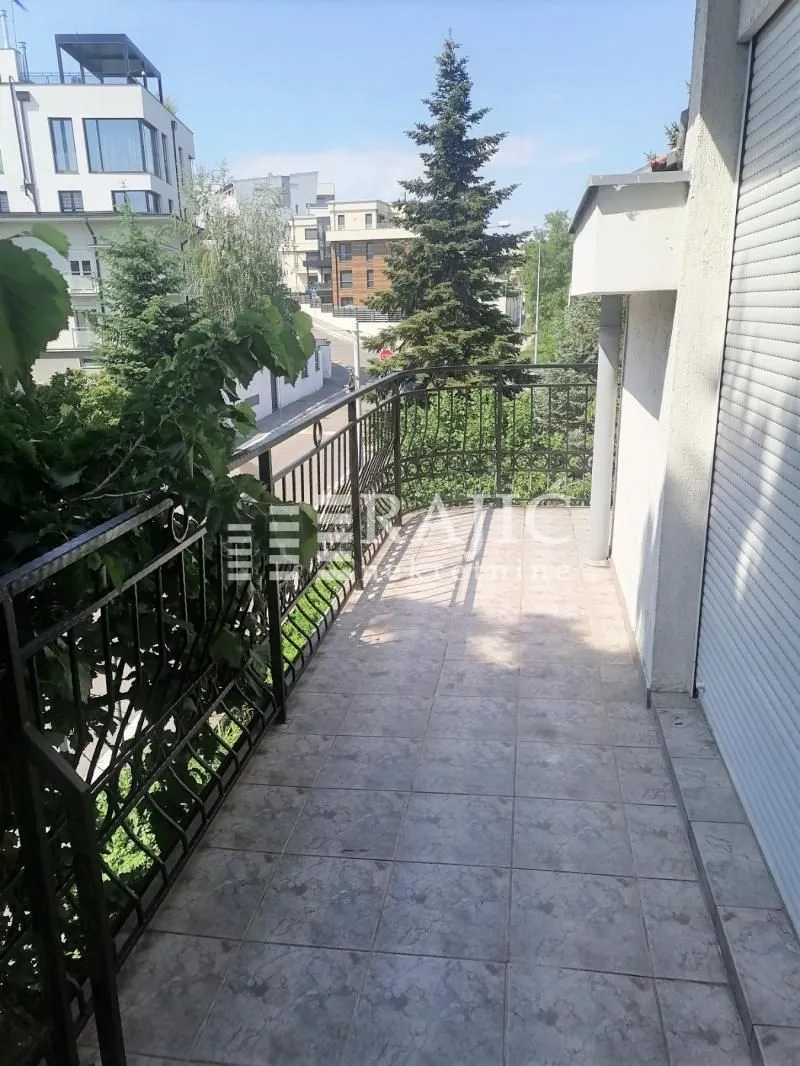 Spacious tiled balcony with metal railing and view of surrounding buildings.