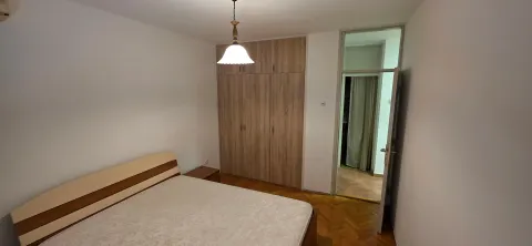Spavaća soba sa bračnim krevetom, drvenim ormarom i parketom. - image 8