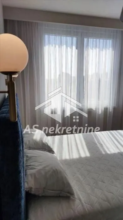 Bedroom with a double bed and a window covered with curtains.