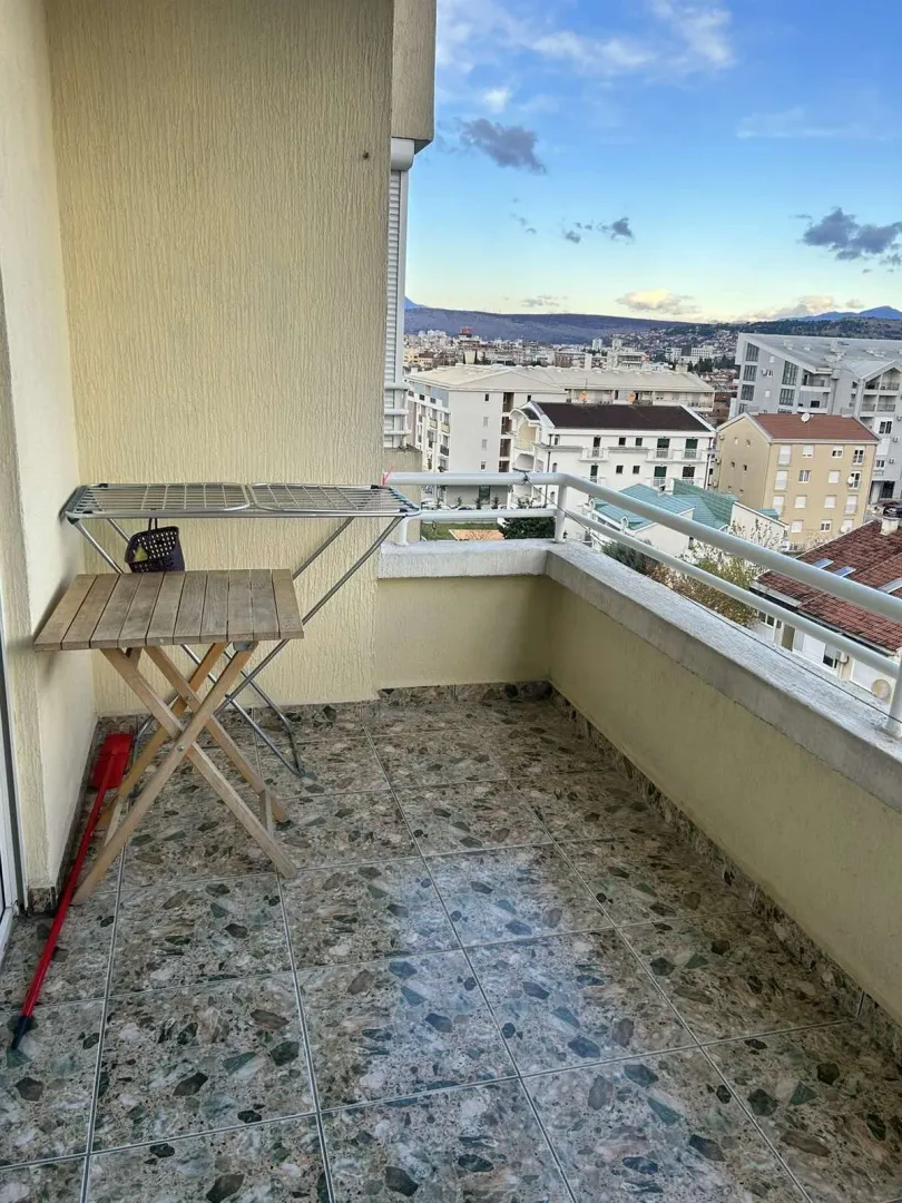Balkon sa pogledom na grad, opremljen sklopivim stolom.