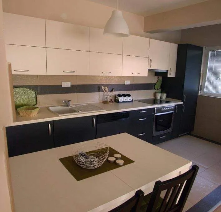 Modern kitchen with white and dark cabinets and a dining table in the foreground.