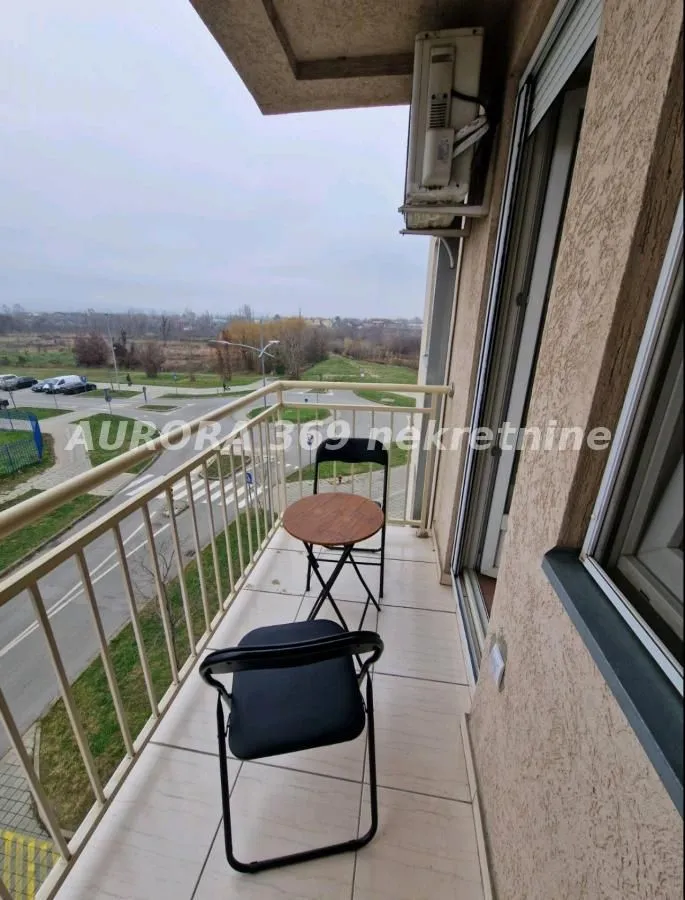 Small furnished balcony with a table and two chairs.